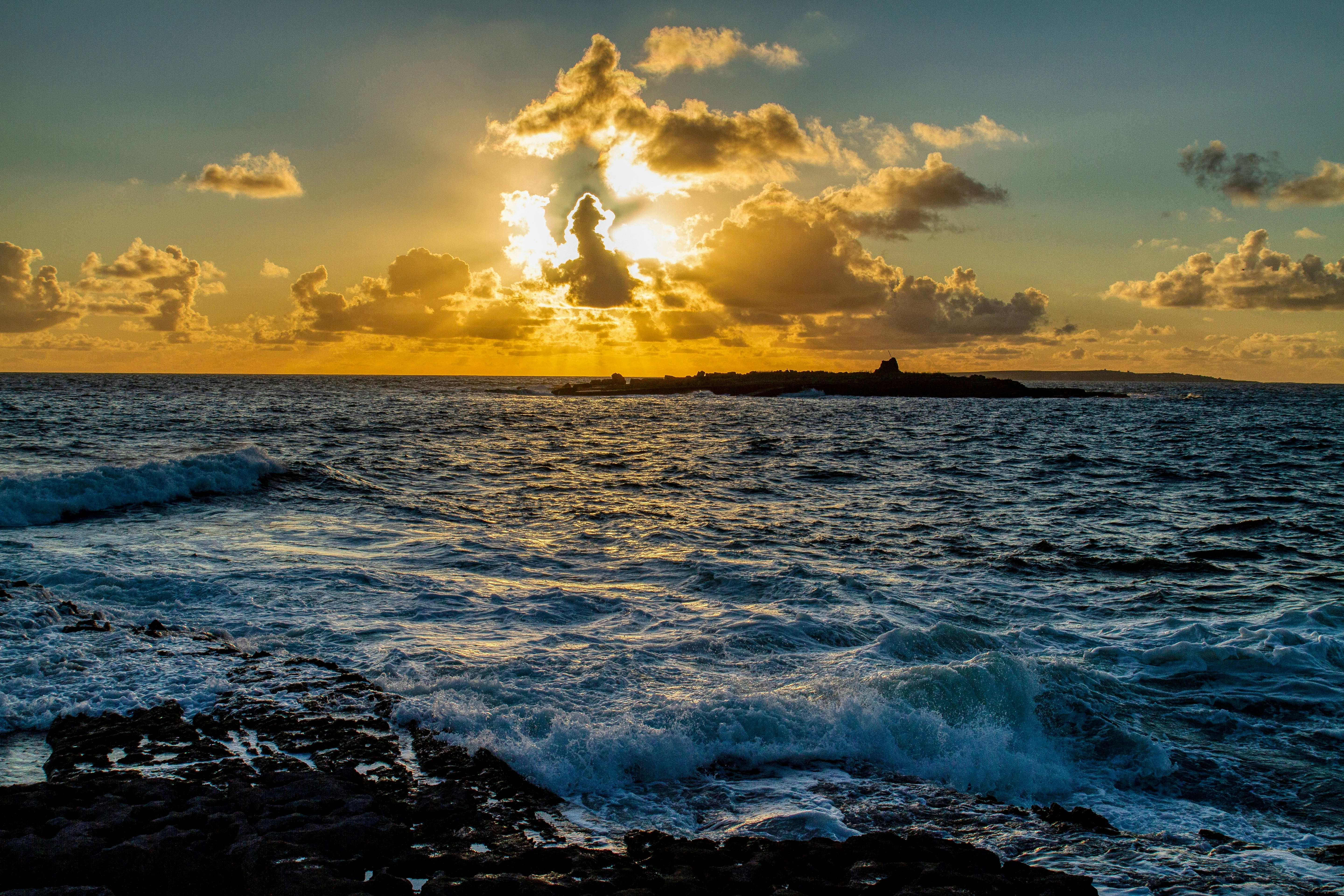 ocean waves crashing on shore during sunset